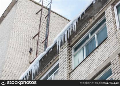 season, housing and winter concept - icicles on building or living house facade