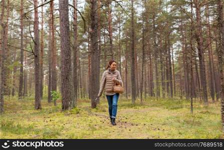 season, leisure and people concept - young asian woman with basket walking in autumn forest and picking mushrooms. young woman picking mushrooms in autumn forest