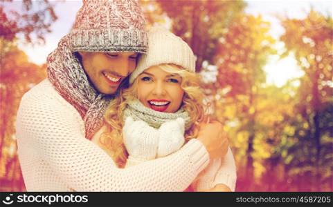 season, people, love and fashion concept - happy family couple in warm clothes over autumn background and sunlight