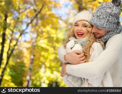 season, people, love and fashion concept - happy family couple in warm clothes over autumn background