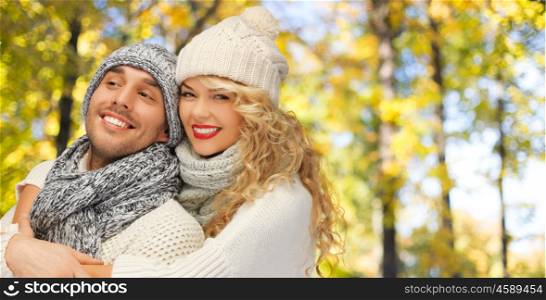 season, people, love and fashion concept - happy family couple in warm clothes over autumn background