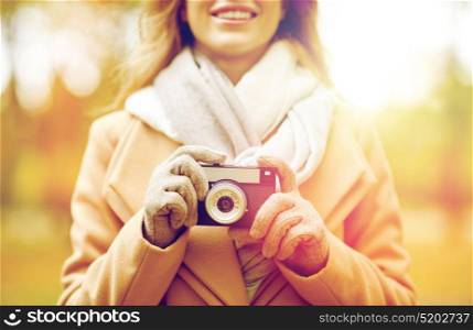 season, photography and people concept - close up of happy smiling young woman taking picture with vintage camera in autumn park. close up of woman with camera in autumn park