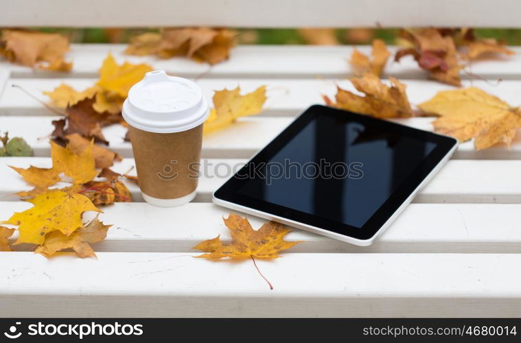 season, technology and advertisement concept - tablet pc computer and coffee paper cup on bench in autumn park