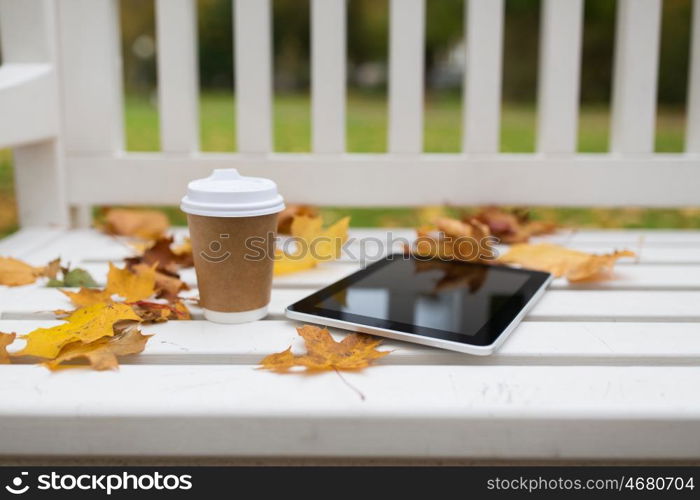 season, technology and advertisement concept - tablet pc computer and coffee paper cup on bench in autumn park