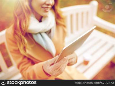 season, technology and people concept - close up of beautiful happy young woman with tablet pc computer sitting on bench in autumn park. close up of woman with tablet pc in autumn park