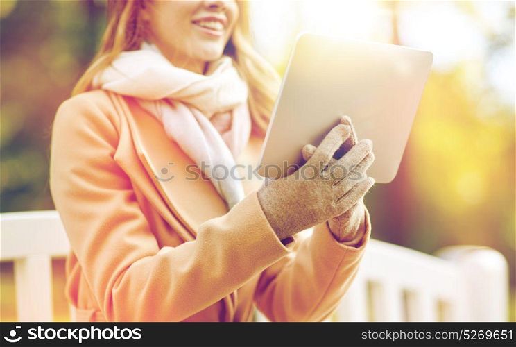 season, technology and people concept - close up of beautiful happy young woman with tablet pc computer sitting on bench in autumn park. close up of woman with tablet pc in autumn park