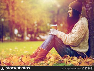 season, technology and people concept - close up of happy young woman drinking coffee from paper cup in autumn park. close up of woman drinking coffee in autumn park