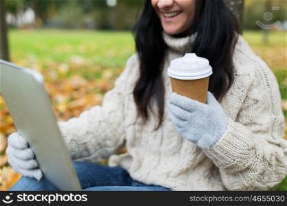 season, technology and people concept - close up of young smiling woman with tablet pc and coffee cup in autumn park