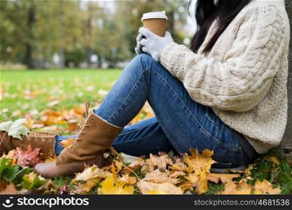 season, technology and people concept - close up of young woman drinking coffee from paper cup in autumn park