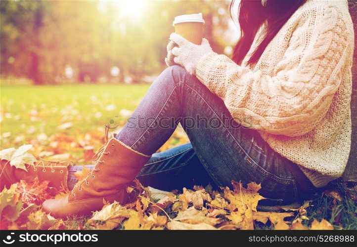 season, technology and people concept - close up of young woman drinking coffee from paper cup in autumn park. close up of woman drinking coffee in autumn park