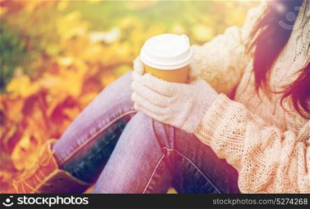 season, technology and people concept - close up of young woman drinking coffee from paper cup in autumn park. close up of woman drinking coffee in autumn park
