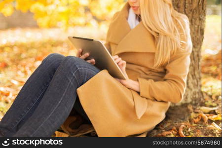 season, technology and people concept - young woman with tablet pc computer in autumn park