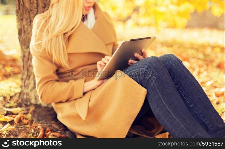 season, technology and people concept - young woman with tablet pc computer in autumn park