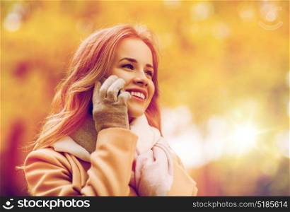 season, technology, communication and people concept - beautiful young woman in autumn park calling on smartphone. woman calling on smartphone in autumn park