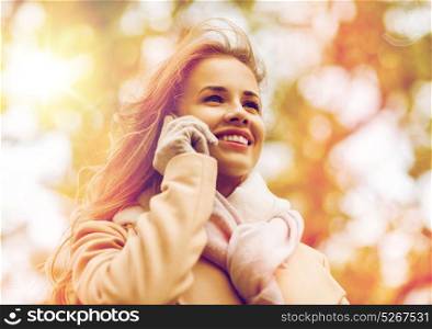 season, technology, communication and people concept - beautiful young woman in autumn park calling on smartphone. woman calling on smartphone in autumn park