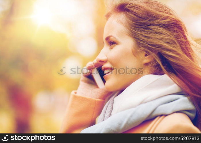 season, technology, communication and people concept - beautiful young woman in autumn park calling on smartphone. woman calling on smartphone in autumn park