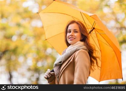season, weather and people concept - beautiful happy young woman with yellow umbrella walking in autumn park