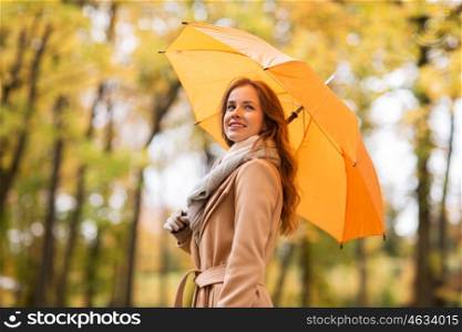 season, weather and people concept - beautiful happy young woman with yellow umbrella walking in autumn park