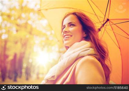 season, weather and people concept - beautiful happy young woman with yellow umbrella walking in autumn park. happy woman with umbrella walking in autumn park
