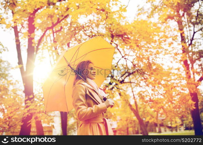 season, weather and people concept - beautiful happy young woman with yellow umbrella walking in autumn park. happy woman with umbrella walking in autumn park