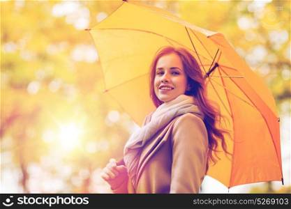season, weather and people concept - beautiful happy young woman with yellow umbrella walking in autumn park. happy woman with umbrella walking in autumn park