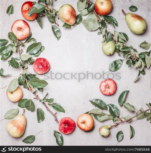 Seasonal garden fruits: apples, pears, peaches with branches and leaves on gray background, top view. Frame. Copy space for your design