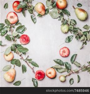 Seasonal garden fruits: apples, pears, peaches with branches and leaves on gray background, top view. Frame. Copy space for your design