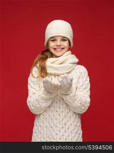 seasonal, people, happiness concept - smiling girl in winter clothes with something on palms