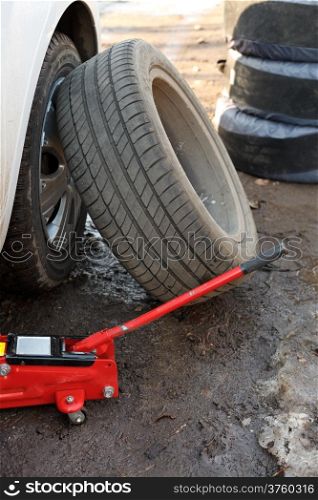 seasonal replacement of tires with jack outdoors - car tire fitting