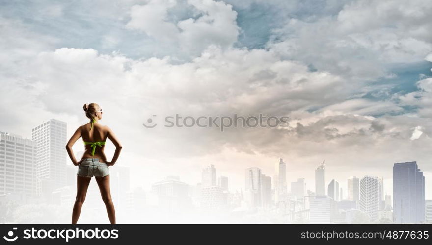 Seasonal sale. Rear view of young pretty woman in bikini and shorts with shopping bags