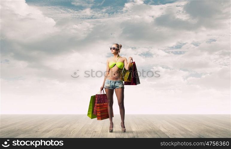 Seasonal sale. Young pretty woman in bikini and shorts with shopping bags