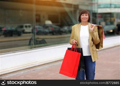 Seasonal Sales. Stylish adult woman with shopping bags. Middle ages female after shopping on shopping mall background. Purchases, discounts, sale concept. Online shopping concept, Black friday.mockup. Seasonal Sales. Stylish adult woman with shopping bags. Middle ages female after shopping on shopping mall background. Purchases, discounts, sale concept. Online shopping concept, Black friday. mockup