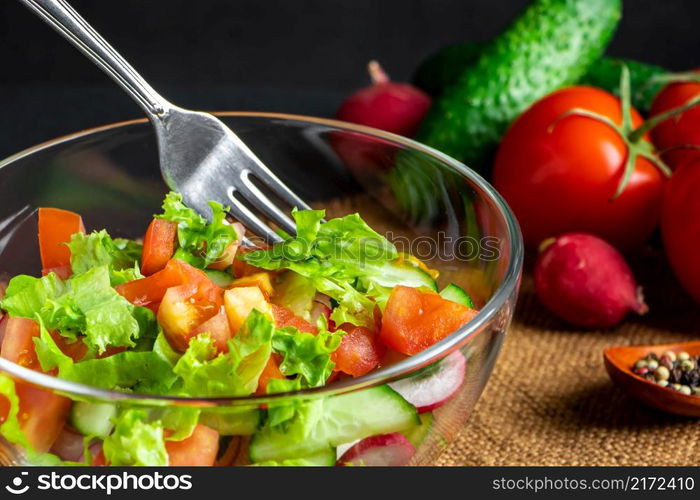 Seasonal summer vegetable salad in a glass bowl on a dark background. Vegan organic food, dietary meal in a rustic style.. Seasonal summer vegetable salad in a glass bowl on dark background. Vegan organic food, dietary meal in a rustic style.