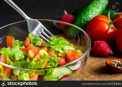 Seasonal summer vegetable salad in a glass bowl on a dark background. Vegan organic food, dietary meal in a rustic style.. Seasonal summer vegetable salad in a glass bowl on dark background. Vegan organic food, dietary meal in a rustic style.