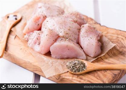 Seasoned raw chicken breast fillets over wooden board, selective focus