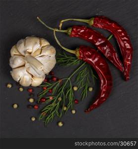 Seasoning ingredients for cooking - spices, pepper mix, chili pepper, garlic, dill. Top view on stone plate