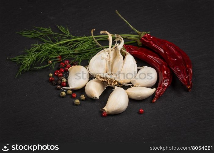 Seasoning ingredients for cooking - spices, pepper mix, chili pepper, garlic, dill. Top view on stone plate