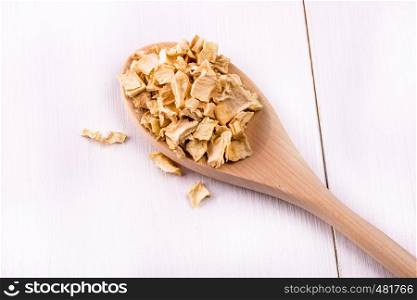 seasoning mixture roots poured into wooden spoon on white wooden table