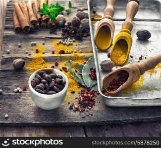 Seasoning with spices in wooden spoons on wooden table in rustic style.