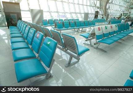 Seat in departure lounge at airport terminal. Distance for one seat keep distance to protect coronavirus and passenger social distancing for safety. Empty seat in the airport. Aviation business crisis