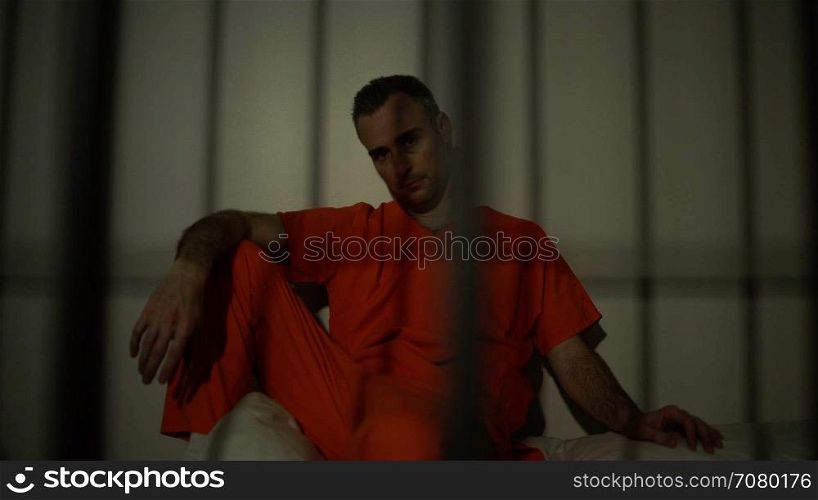 Seated inmate in prison stares down the camera