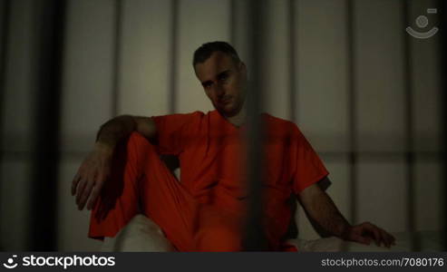 Seated inmate in prison stares down the camera