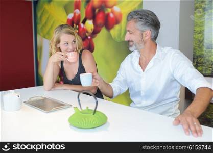 Seated man and lady with hot drinks