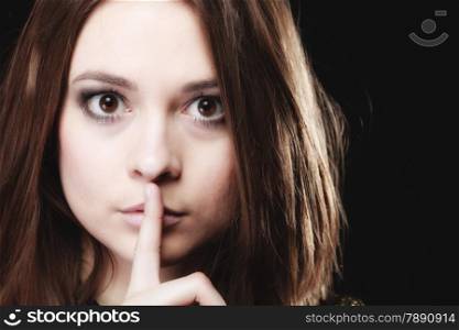 Secret woman finger on lips. Teen girl showing hand silence sign, saying hush be quiet on black