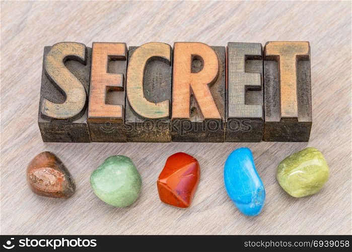 Secret word abstract in vintage letterpress wood type with colorful, polished gemstones