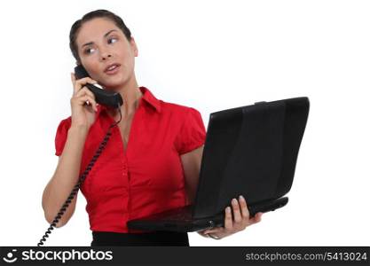 Secretary holding a laptop while talking on the phone