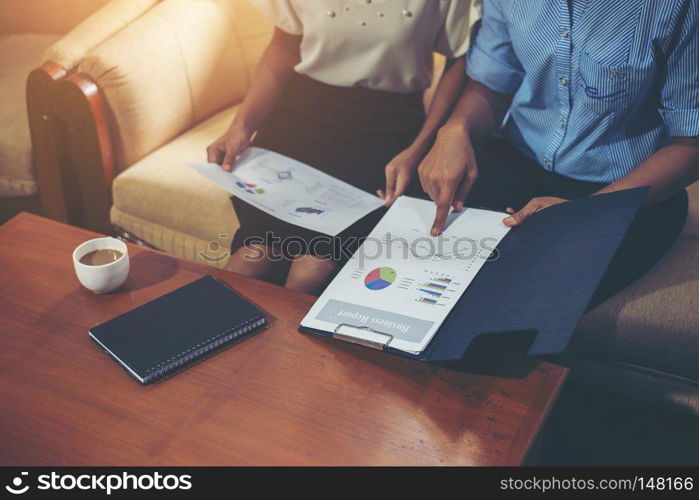 Secretary pointing her hands to explain financial graph to her partner.. Secretary pointing her hands to explain financial graph to her p