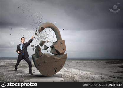 Security concept. Businessman breaking stone lock with karate kick