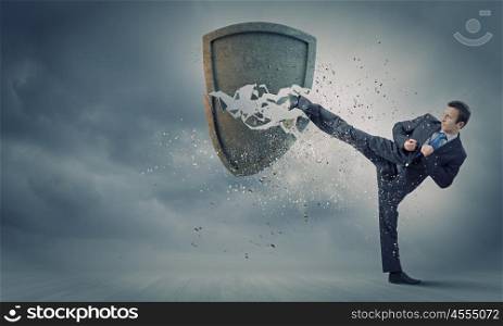Security concept. Businessman breaking stone shield with karate punch