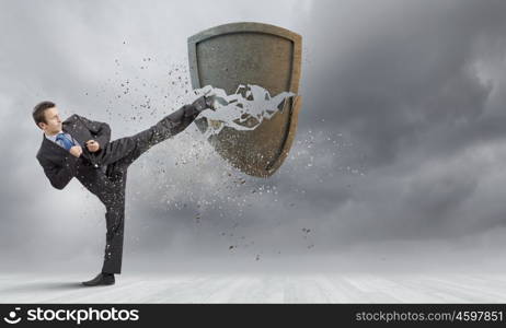 Security concept. Businessman breaking stone shield with karate punch
